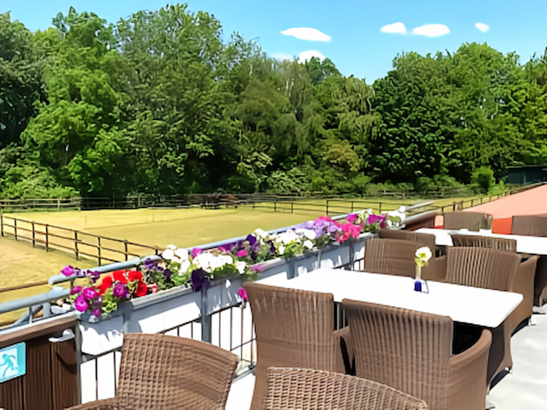 Sonnenterrasse eines Restaurants mit eingedeckten Tischen